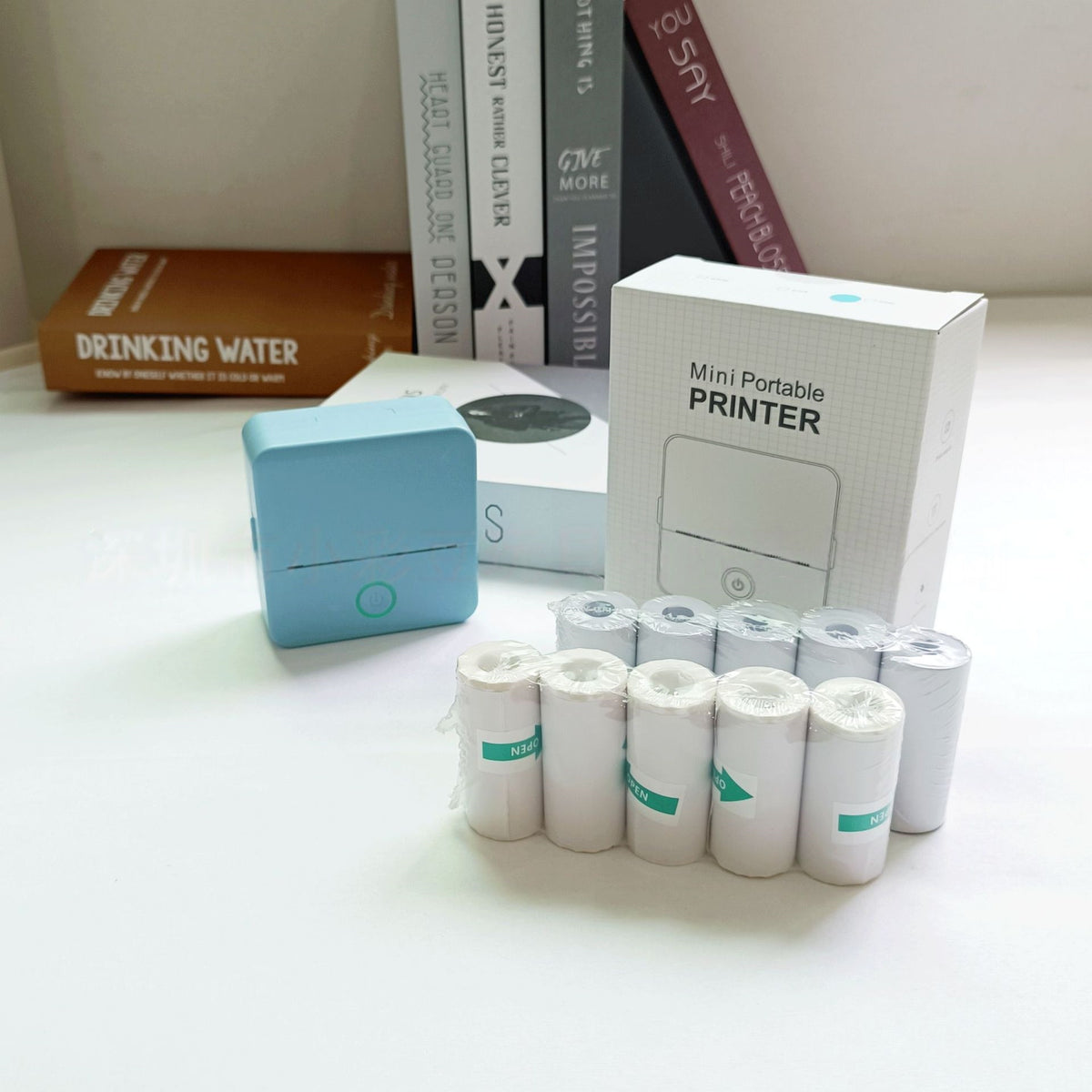 Mini portable printer with rolls of paper and packaging on a surface