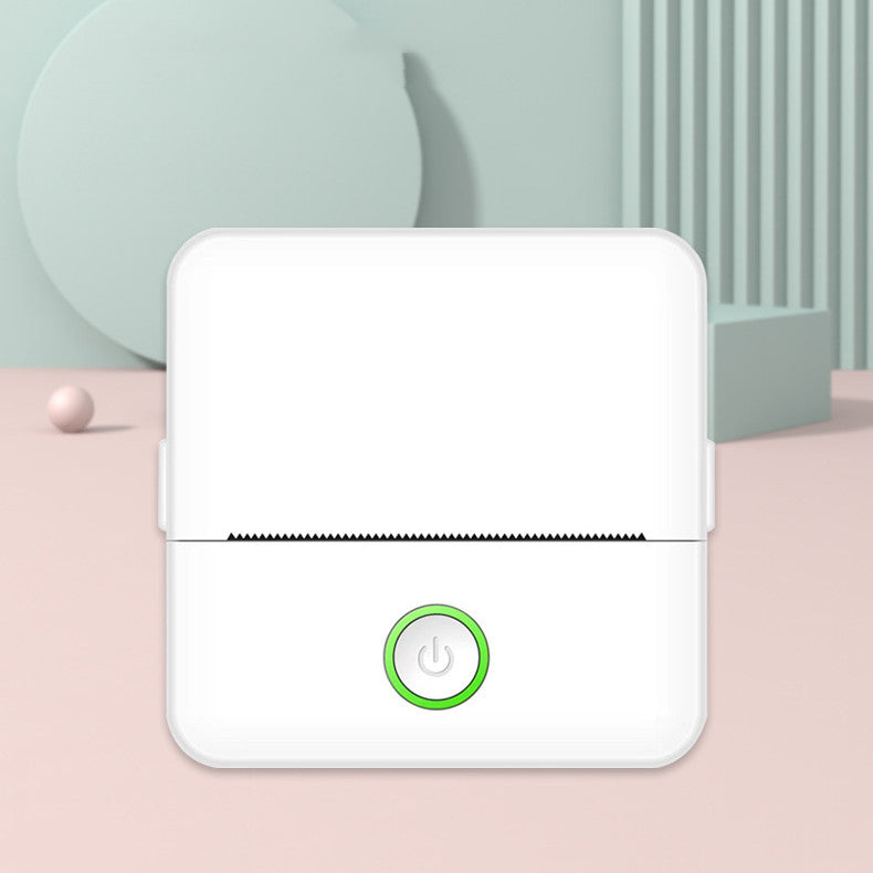 White electronic device with a green power button on a light pink surface
