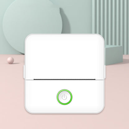 White electronic device with a green power button on a light pink surface