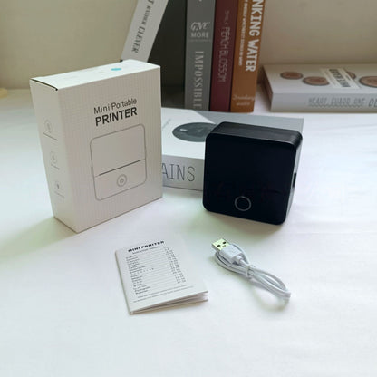 Mini portable printer with packaging and accessories on a table