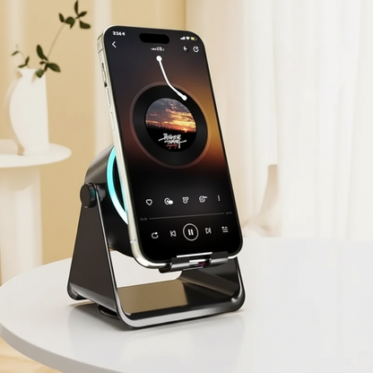 A black magnetic wireless phone stand holding an iPhone, set on a white round table in a bright, modern room with soft beige walls and curtains.